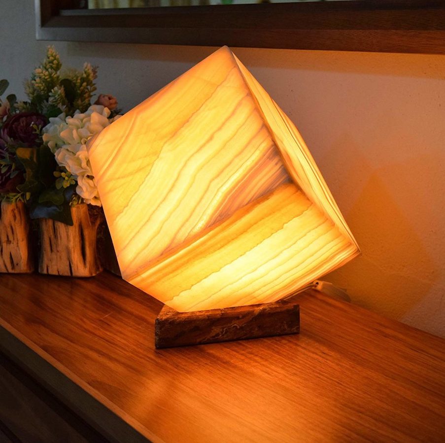 Orange cube onyx table lamp made of Miel marble collection is standing on the table with the light on