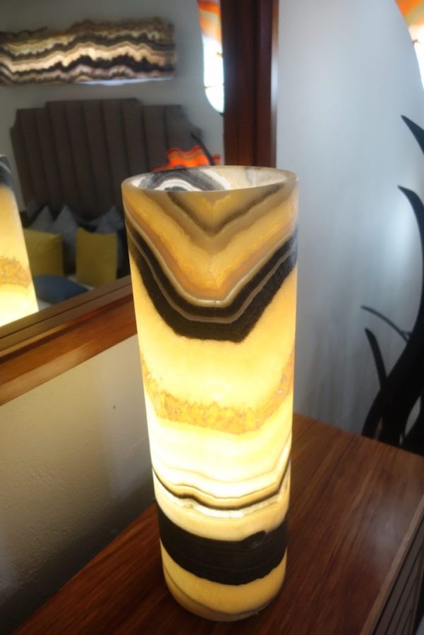 Onyx Cylindrical Table Lamp with Open Top next to the Mirror. Colors range from light yellow to black.