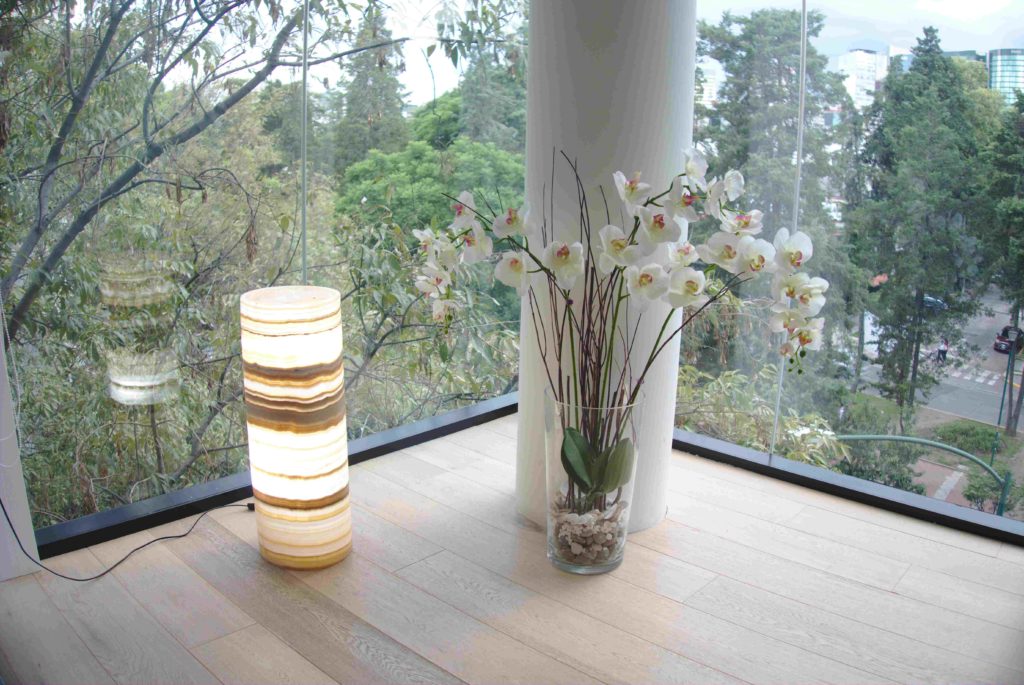 Onyx stone cylindrical floor lamp from Ambar collection with lights on. Lamp's height is over 100 cm.
