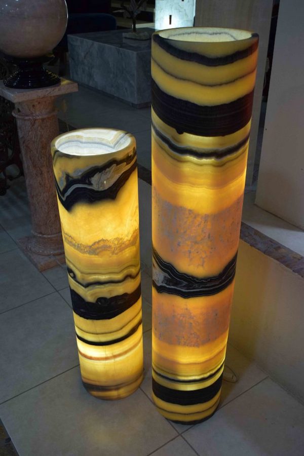 Two Onyx Cylindrical Floor Lamps with Open Top Standing Next to Each Other from Galactea Collection. Colors range from intense yellow to black.