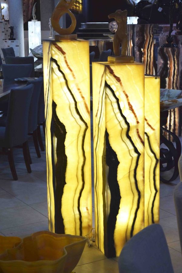 Three rectangular onyx floor lamps of different height made of Galactea stone collection. The lamps have vertical betas with primary colors being yellow, black and dark brown.