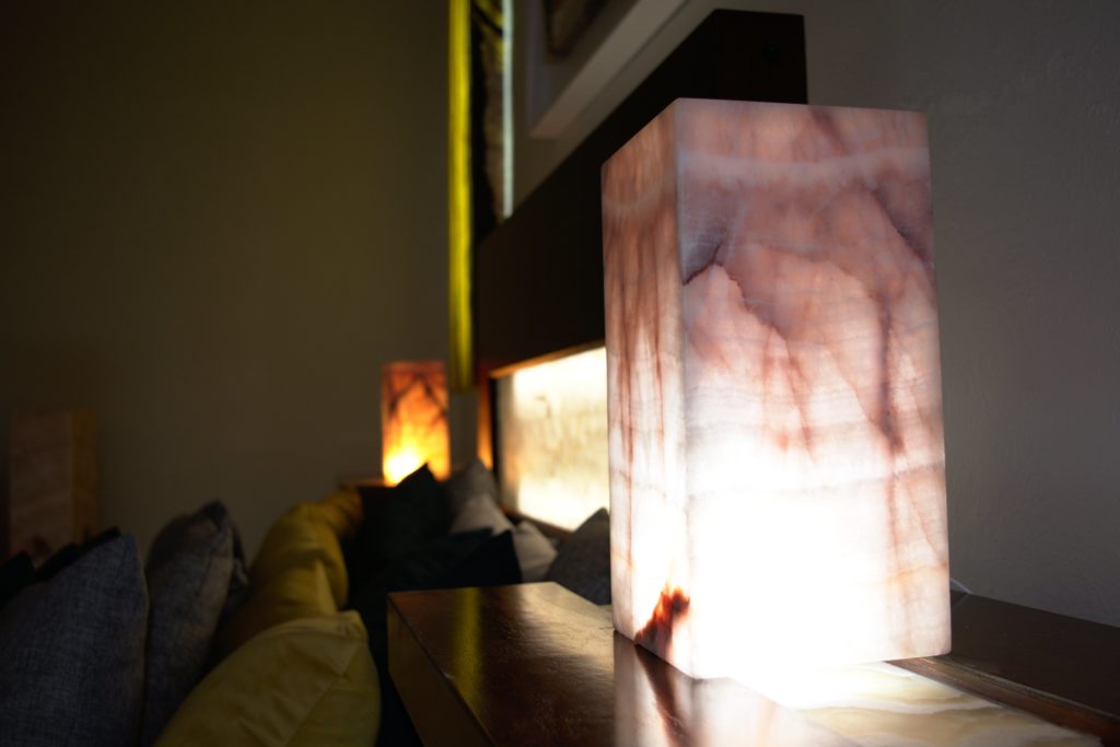Two Rosa Cristal onyx table lamps standing on the both sides of the bed with light on