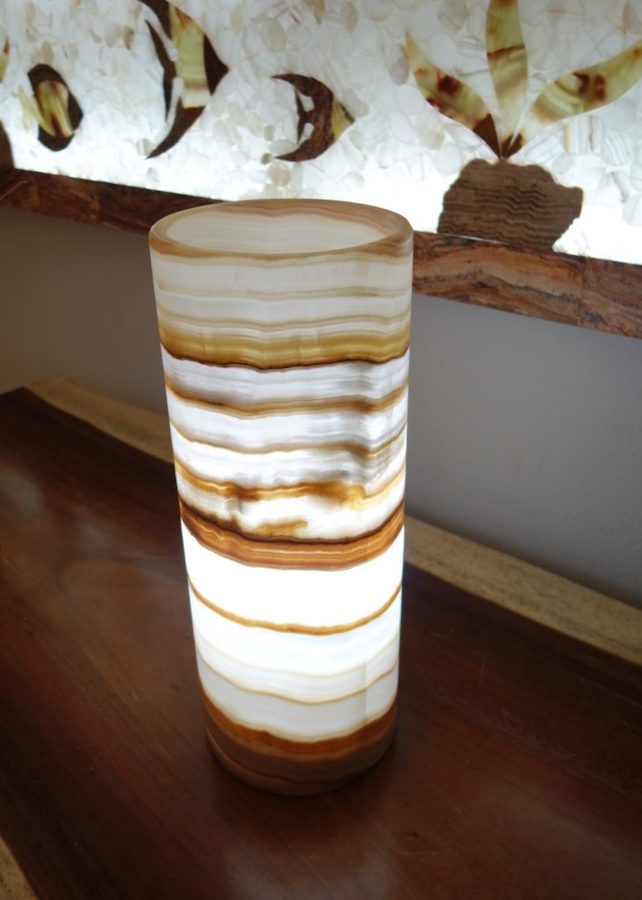 Onyx Ambar cylindrical table lamp with lights on. Colors: Orange, Yellow, Brown, and White