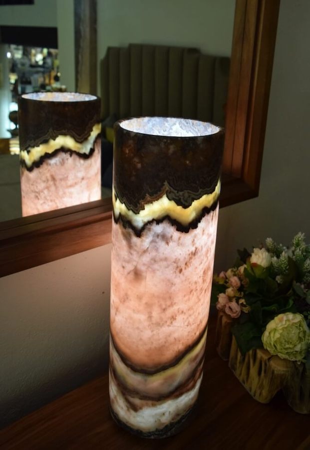 Midsize cylindrical table lamp made of Onyx Beta Rosa stone standing next to the mirror