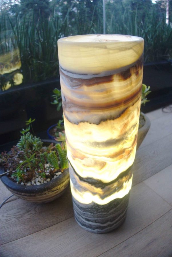 Onyx Galactea cylindrical floor lamp with light on standing next to the panoramic window