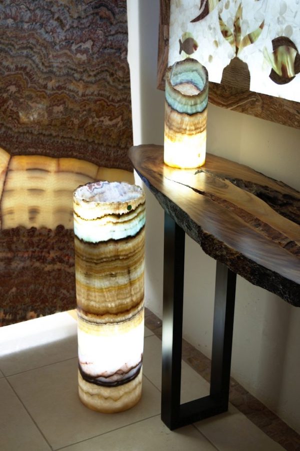 Two onyx lamps made from Serpentina Beta Azul stone collection. Floor lamp with open top is standing next to the table lamp with open curved top. Light on.